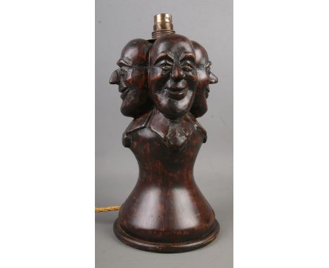 A wooden Folk Art table lamp, with four mask decoration. (Height approximately 29cm).  