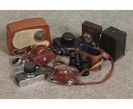 A collection of vintage cameras including Koura, Ricoh and kodak examples with a set of binoculars and radio.  