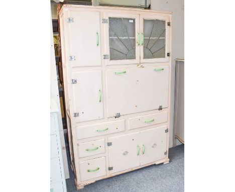 A circa 1930's kitchen cabinet, cream painted with green bakelite handles and two leaded cupboard doors, 114cm by 43cm by 179