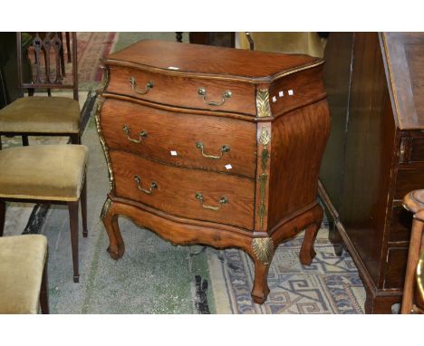 A reproduction bombe commode, serpentine top, three drawers, sing handles, gilt metal mounts.