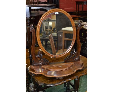 A late Victorian walnut dressing mirror, oval plate, shaped and carved uprights, serpentine front, hinged cover to trinket bo