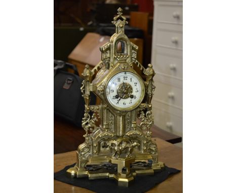 A Victorian brass Gothic revival clock, cream and gilt dial, Arabic numbers, cast Gothic arching case, chiming movement, c. 1