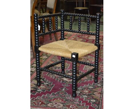 An Arts and Crafts bobbin turned corner chair, rush seat