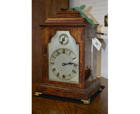 An early 20th century oak bracket clock, arched silvered dial, Roman numerals, single winding hole, subsidiary fast/slow chap