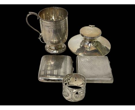 Five silver items comprising two cigarette cases, capstan inkwell, christening mug and napkin ring.