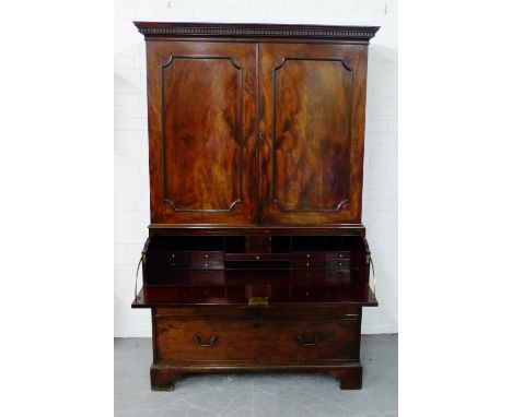 A 19th century mahogany linen press, the rectangular top with a dentil frieze above a pair of cupboard doors, over a secretai