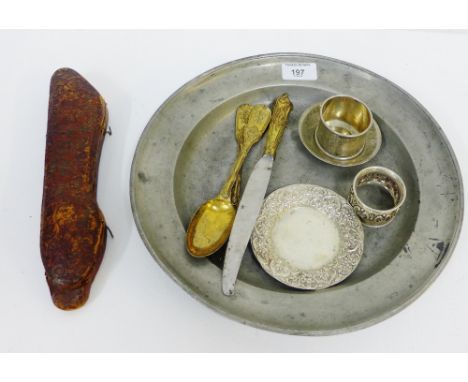 A gilt metal three piece cutlery set comprising spoon, fork and knife in a leather fitted case, together with a silver napkin