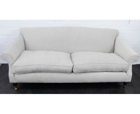 A contemporary three seater grey upholstered sofa, on mahogany supports with brass caps and castors, 80 x 210cm