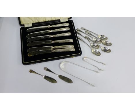 A mixed lot of silver flatware to include a set of six silver handled butter knives, various teaspoons, sugar tongs and small