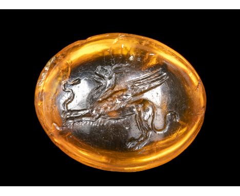 A FINE ROMAN CITRINE INTAGLIO. GRIFFIN KILLING A SNAKE. 1st century A.D.12x15x6 mmThe winged creature faces left, in the act 