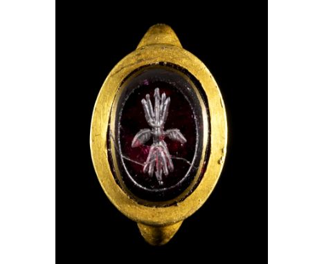 A LATE GREEK HELLENISTIC GOLD RING WITH A GARNET INTAGLIO. THUNDERBOLT. 3rd - 2nd century B.C. Stone 10x14 mm; int. size 13x1