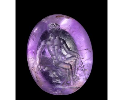 A ROMAN AMETHYST INTAGLIO. SEATED MALE FIGURE. 2nd century A.D.9 x 11 x 5 mmA young man seated, naked on rocks. With his righ