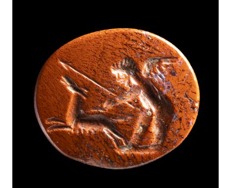 A ROMAN RED JASPER INTAGLIO. EROS HUNTING WITH A DOG.2nd century A.D.8 x 10 x 2 mmThe winged god is facing left holding a spe