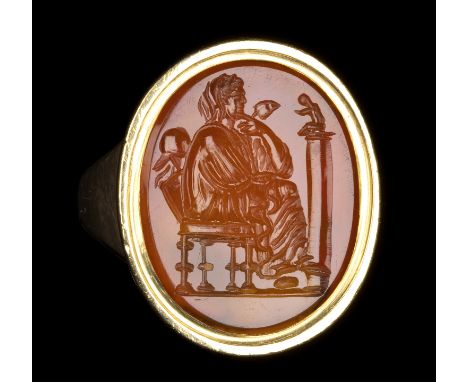 A GRAND TOUR CARNELIAN INTAGLIO SET IN A GOLD RING. SEATED MUSE.  End of 18th century Stone 13 x 17 mm; internal size 17 mm.7