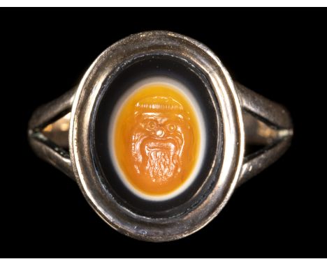 A ROMAN AGATE INTAGLIO SET IN A GOLD RING. THEATRICAL MASK. 1st century B.C. - 1st century  A.D.Stone 10x13 mm; int. size 17x