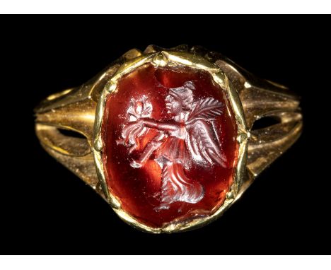 A ROMAN GARNET INTAGLIO SET IN A LATER GOLD RING. NIKE. 1st century B.C. - 1st century A.D. Stone 11x13 mm; Int. Size 16,5x17