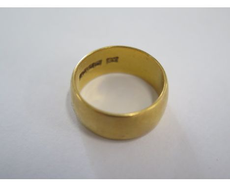 A hallmarked 22ct yellow gold band ring size N - 8mm band - approx weight 9.4 grams - some usage marks but no damage 