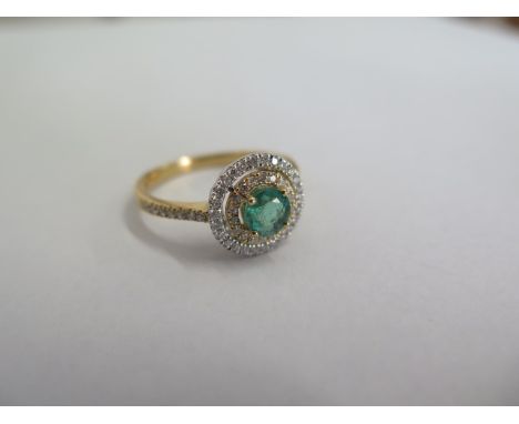 A hallmarked 18ct yellow gold emerald and diamond Halo ring size O - the central emerald approx 0.48ct - total diamond weight