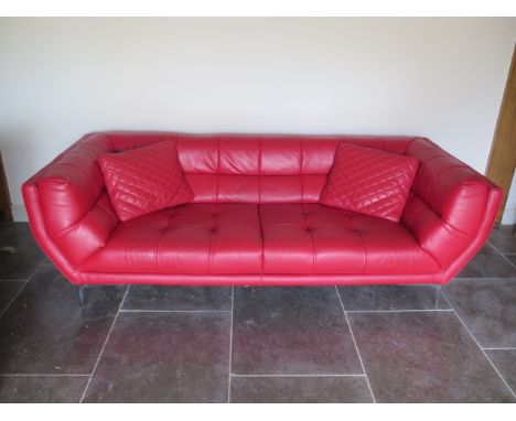 A designer red leather two seater sofa with two cushions - Height 75cm x 234cm x 92cm - in reasonably good condition 