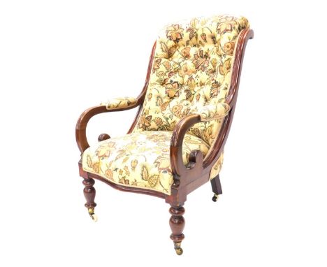 A Victorian mahogany show frame armchair, with button padded arms and seat, on turned legs with castors.