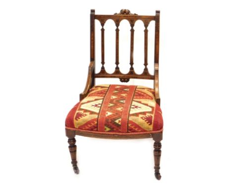 A Victorian walnut and burr yew nursing chair, with a rail back and a padded seat, on turned legs with ceramic castors.
