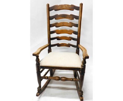 A ash and elm ladder back rocking chair, with shaped arms, padded seat on turned supports.