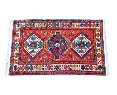 A Kazakh Caucasian rugthe red field with central blue medallion and two further ivory medallions, enclosed within ivory borde