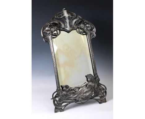 An Art Nouveau pewter easel-backed mirrorcast with a reclining female, leaf and berries amongst sinuous lines, shaped rectang