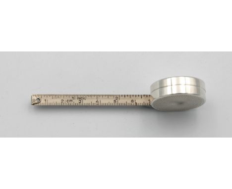 Continental silver (white metal) circular tape measure case with engine turned decorationand a one metre steel tape 3.0 cm. d
