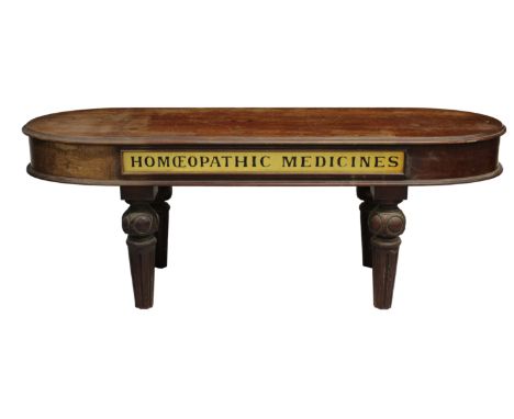A Victorian mahogany oval chemist display table the stepped oversailing top above a deep frieze, inset with a plaque inscribe