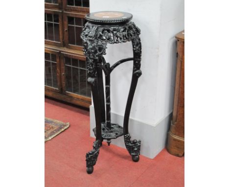 A Chinese Ebonised Jardiniere Stand, circa 1900, with red marble inset to circular top, heavily carved with foliage, on three