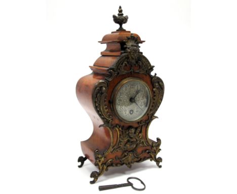 A Late XIX/Early XX Century Mantel Clock, the walnut case applied in gilt metal with mask heads, fruit and scrolls, the white