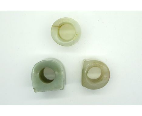 A Chinese Pale Green Jade Archers Ring, of plain circular form, 3.2cm diameter; Another Similar and a Dark Green Jade Example