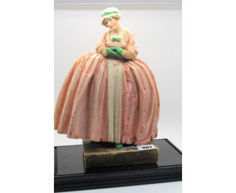 A 1930's Composition Model of Polly Peachum, wearing a long pink dress, green gloves and a bonnet, 27cm high, on a hardwood s