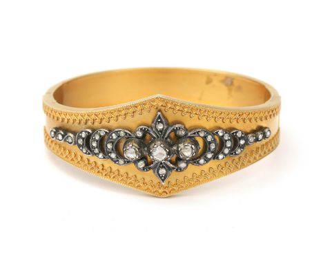 A 14 karat gold bracelet with rose cut diamonds. A tapered rigid bangle with a silver rose cut diamond applique at the front,