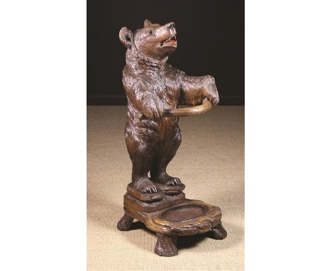 A 19th Century Black Forest  Linden Wood Umbrella/Stick Stand carved in the form of a bear with inset glass eyes and painted 