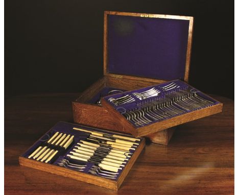 An Oak Canteen of Silver Plated Cutlery. The fitted box with two lift-out trays lined in blue baize and accommodating; a grav