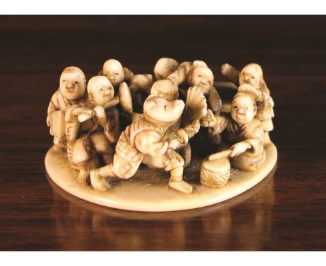 A 19th Century Ivory Netsuke intricately carved in the form of eight dancing musicians, 2 ins (5 cms) in length.