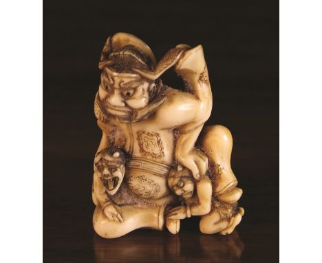 A Fine 19th Century Ivory Netsuke carved in the form of Shoki The Demon-Queller depicted with two demons, 1¾ ins (4.5 cm) in 