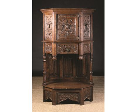 A 19th Century French Renaissance Style Oak Dressoir. The canted cupboard carved in relief with protuberant heads encircled b