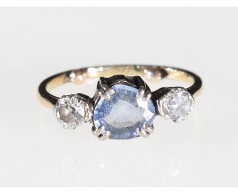 A contemporary three stone ring with two diamonds flanking a pale blue stone, possibly a sapphire, the diamonds are half a ca