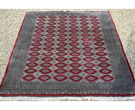 A large Pakistani Turkoman design carpet, red ground with repeating gul design and multi-borders, 370 x 280 cm, signed to cor