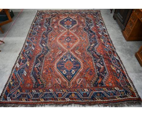 A Persian Shiraz carpet with navy medallions on terracotta ground, 310 x 210 cm&nbsp; 