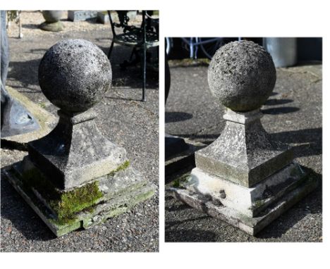 A large pair of antique weathered cast stone ball finial pier caps, raised on tapering form square bases, each 70 cm h o/all 