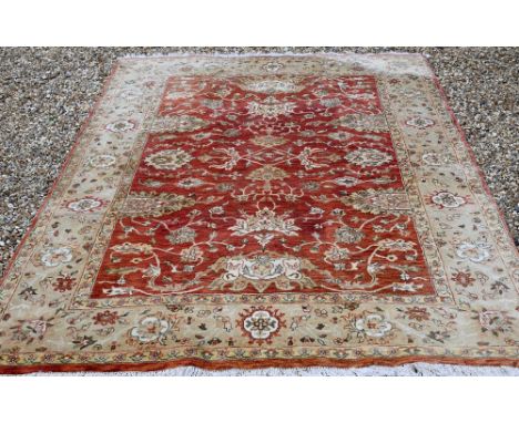 An Indian Agra carpet, traditional floral design on terracotta field, beige rosette border, 274 cm x 190 cm 