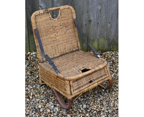 A vintage 1950s rattan wicker fishing chair with folding back supports by two leather straps