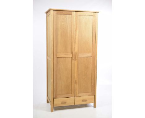 A modern light oak wardrobeWith two panelled doors enclosing a single shelf above two drawers raised on block feet, 90x191x60