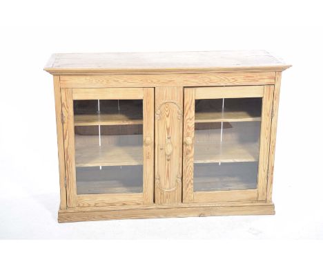 A Victorian pine glazed two door cabinetWith a central moulded panel flanked by two glazed doors each with turned wooden hand