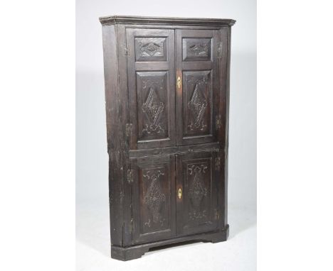 A 17th/18th Century oak freestanding corner cupboardWith a moulded cornice above a pair of panelled doors each centred with a