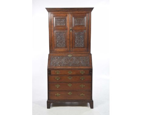 A George III carved oak bureau bookcaseWith a moulded dentil cornice over a pair of panelled doors each with scrolling foliat